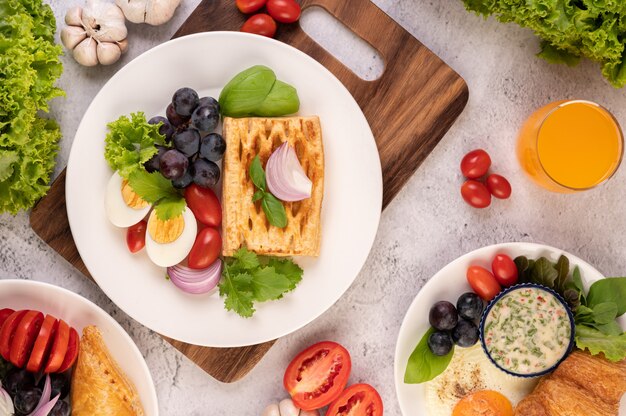 아침 식사는 빵, 삶은 계란, 검은 포도 샐러드 드레싱, 토마토 및 얇게 썬 양파로 구성됩니다.