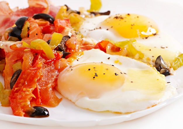 Breakfast - fried eggs with bacon, tomatoes, olives and slices of cheese