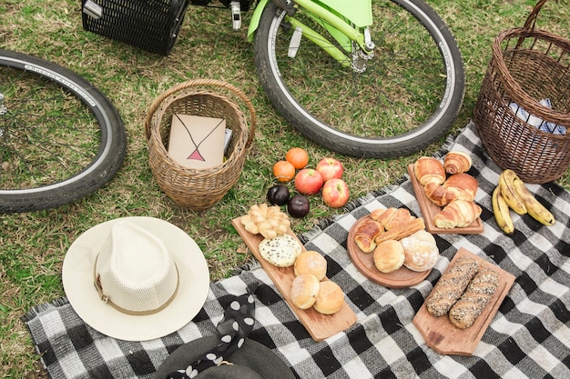 Foto gratuita prima colazione; cappello; cesto e bicicletta al picnic nel parco