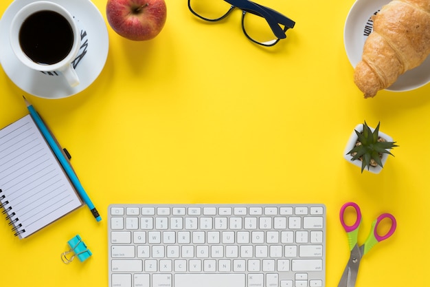 Breakfast; office stationeries and keyboard on yellow background for writing the text