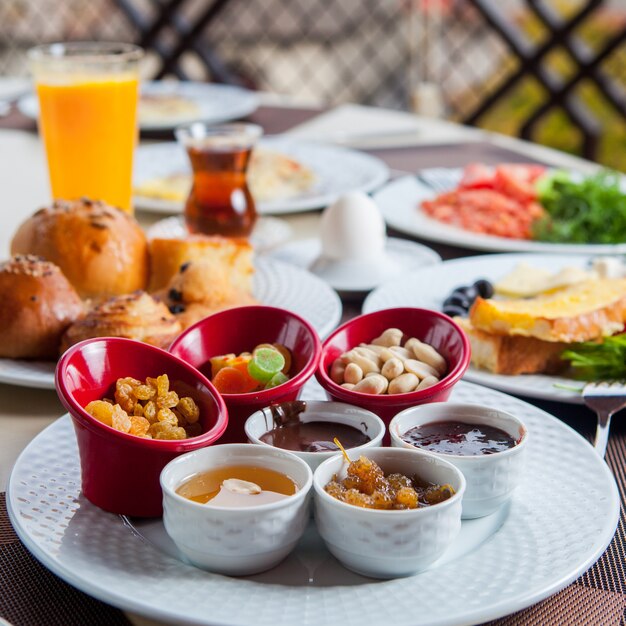 Breakfast outside with nuts, dried fruit, honey, orange juice, tea side view