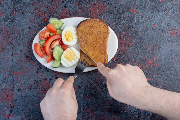 Breakfast plate with egg, cucumber, tomato and bread slices. 