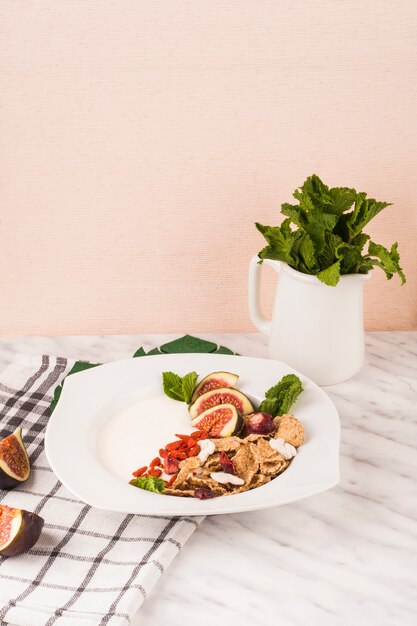 Breakfast plate with jug of mint leaves and kitchen napkin on white marble