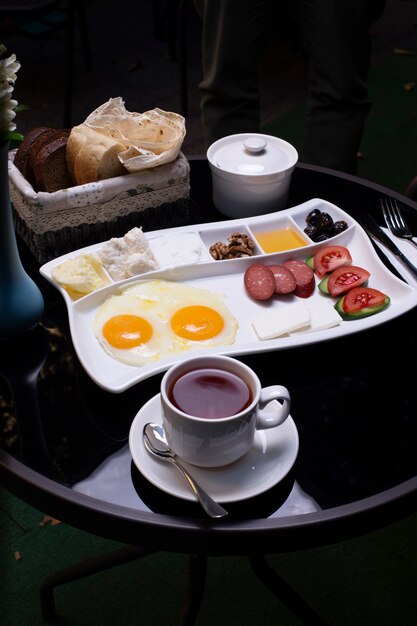 Breakfast plate with variety of foods, a cup of tea and bread.