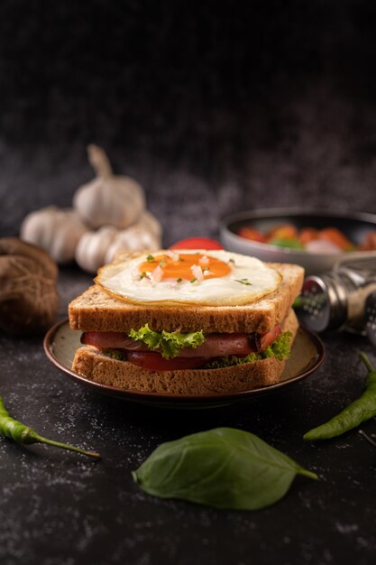 Breakfast sandwich made with bread, fried egg, ham, and lettuce.