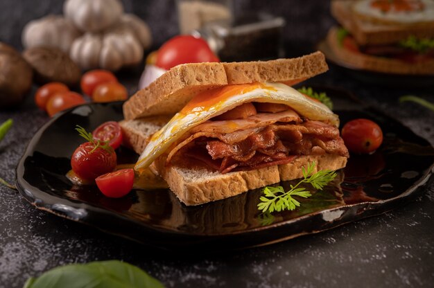 Breakfast sandwich made with bread, fried egg, ham, and lettuce.