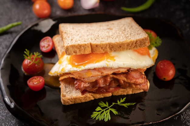 Breakfast sandwich made with bread, fried egg, ham, and lettuce.