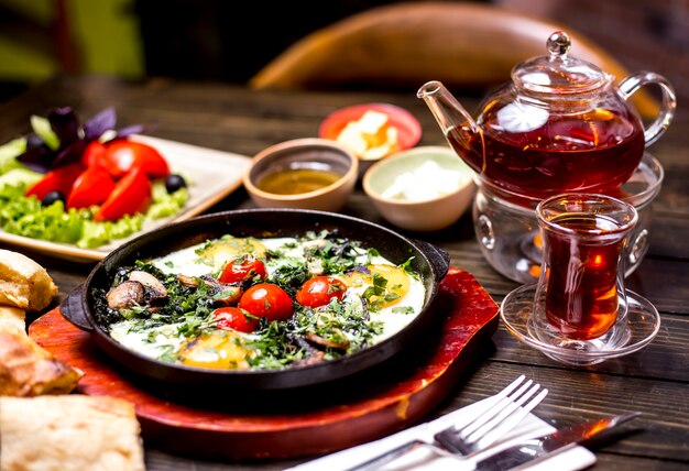 Breakfast set eggs tomato butter honey pot of tea side view