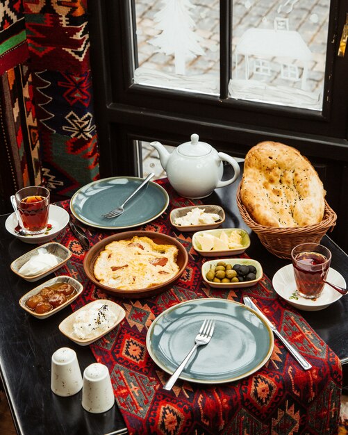 Breakfast setup with egg and sausages dish fig jam olive butter cheese and tea