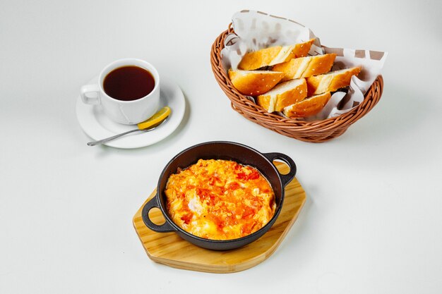 Breakfast setup with egg and tomato dish black tea and bread