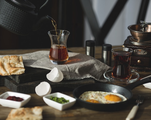 Breakfast table set for two persons with tea glasses and fried eggs