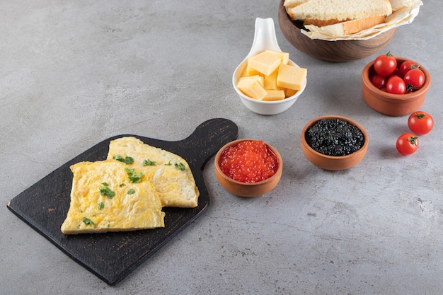 Breakfast table with omelet and caviar placed on a stone surface. 