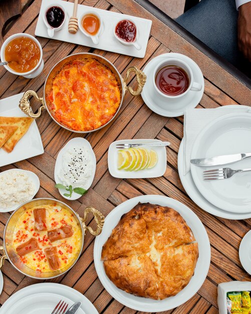 Breakfast table with variety of foods and cup of tea.