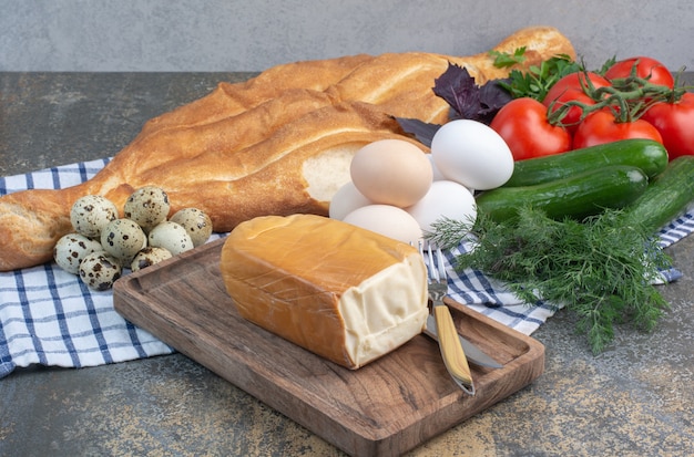 Breakfast table with vegetables, bread, eggs and cheese.