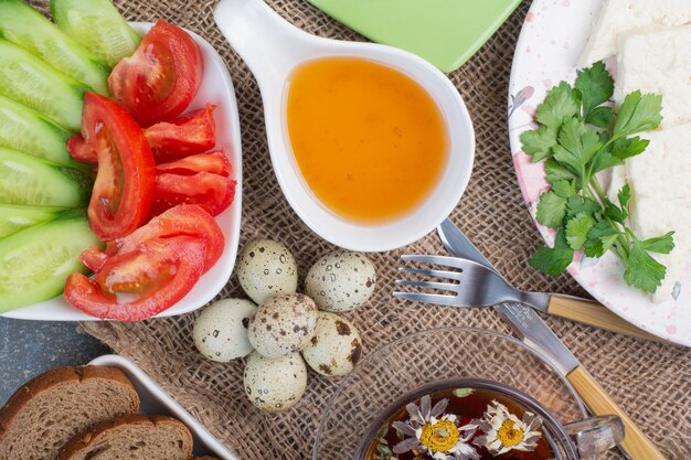 Breakfast table with vegetables, tea, bread and eggs