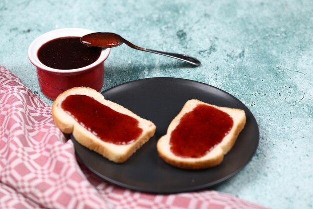 아침 식사는 잼 검은 접시에 토스트.