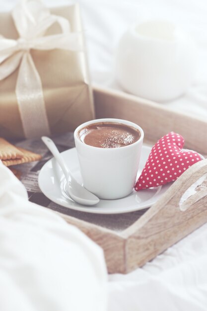 Breakfast tray with a coffee, a heart and a golden gift