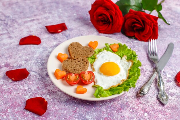 발렌타인 데이에 아침 식사-달걀 프라이와 심장 모양의 빵과 신선한 야채.