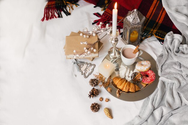 breakfast with donuts, croissant, cookies and tea cup on a tray in bed