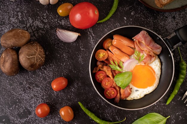 토마토와 함께 냄비에 튀긴 계란, 소시지, 햄으로 아침 식사. 칠리와 바질