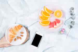 Foto gratuita colazione con frutta e cellulare