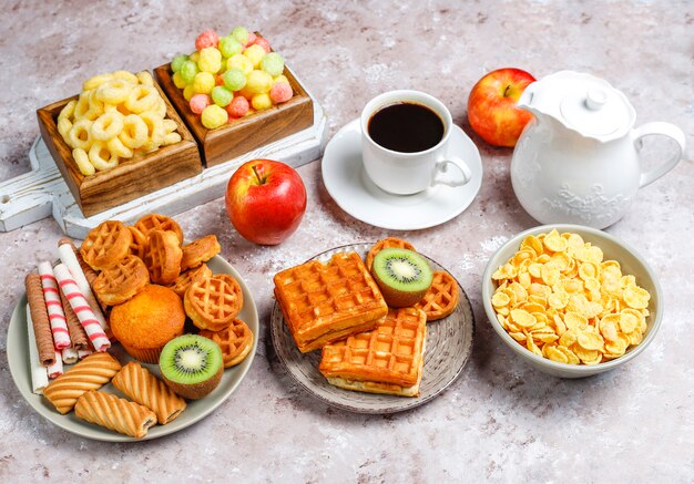 Breakfast with various sweets, wafers, corn flakes and a cup of coffee, top view