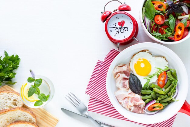 Breakfast for your beloved for the holiday heartshaped egg bacon green beans on a white table Selective focus View from above Copy space