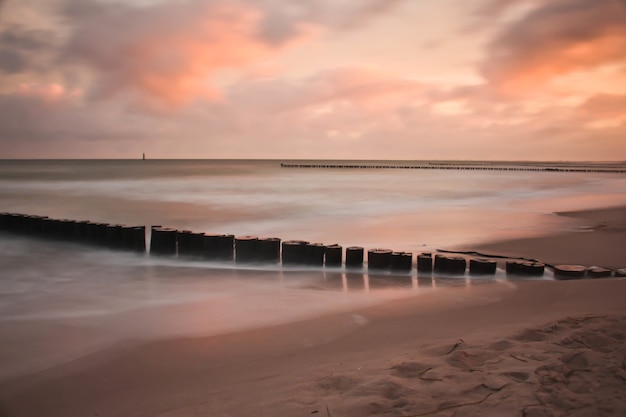 Бесплатное фото Волнорез на песчаном пляже во время заката