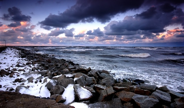 Breakwater with snow at sunset