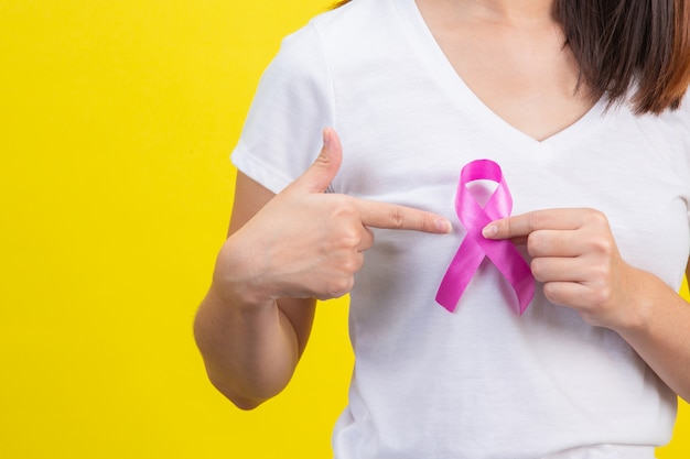 Рак молочной железы, женщина в белой футболке с атласной розовой лентой на груди, символ осведомленности о раке молочной железы