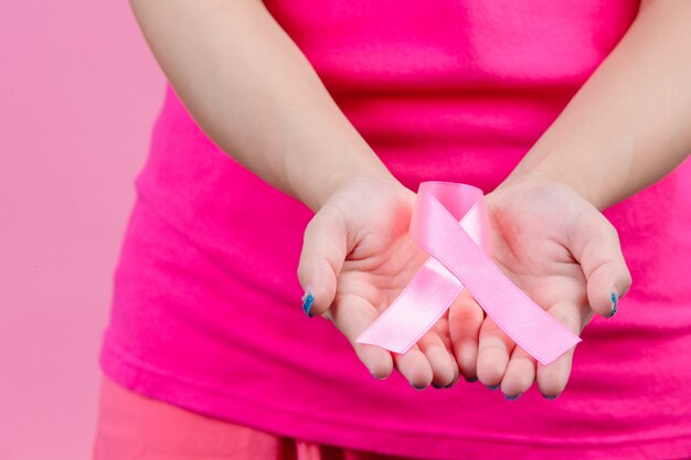 乳がんの意識、両手に女性に置かれたピンクのリボンは、世界乳がんデーのシンボルです。