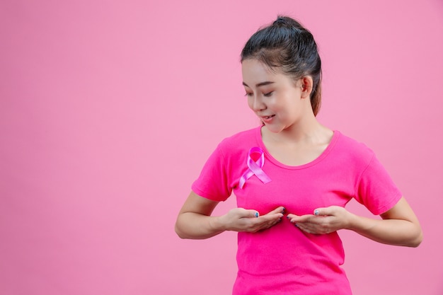 Breast cancer awareness , Woman in pink t-shirt with satin pink ribbon on her chest, supporting symbolbreast cancer awareness 