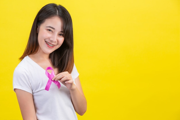 Breast cancer , a woman in a white T-shirt with a satin pink ribbon on her chest, a symbol for breast cancer awareness 