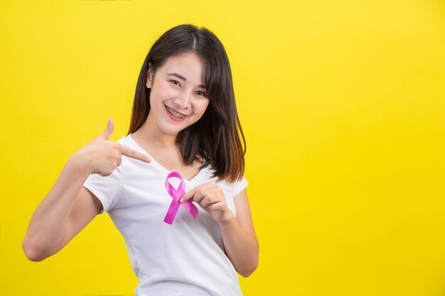 Рак молочной железы, женщина в белой футболке с атласной розовой лентой на груди, символ осведомленности о раке молочной железы