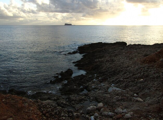흐린 날에 몰타에있는 Filfla의 섬으로 바다 위로 일몰을 가져가는 호흡