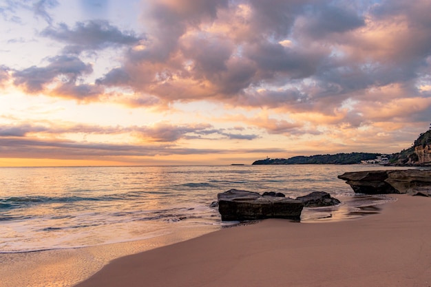 美しい夕日と岩場のビーチの息をのむような風景