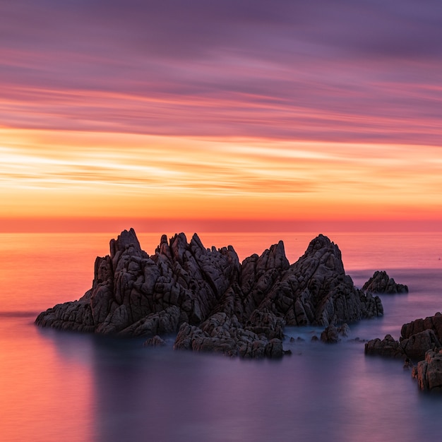 Foto gratuita paesaggi mozzafiato di faraglioni durante il tramonto sotto il cielo colorato a guernsey