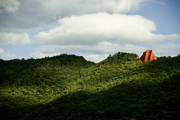 Breathtaking shot of amazing hill landscape under a sunlight and cloudy sky