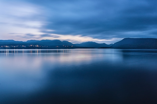 Free photo breathtaking shot of a deep blue ocean and a mountain range on a dark and cloudy day