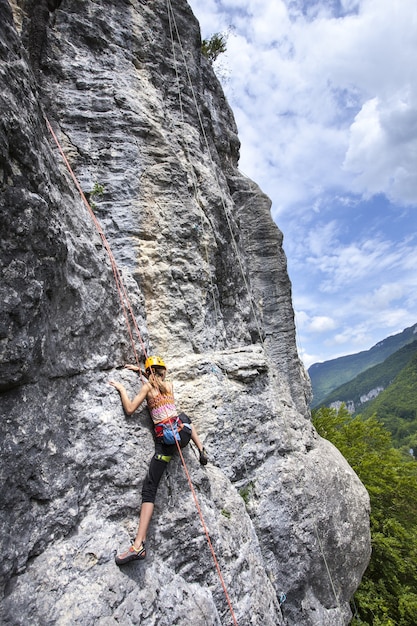 Breathtaking shot of a female climbing on the high rock in  Champfromier, France