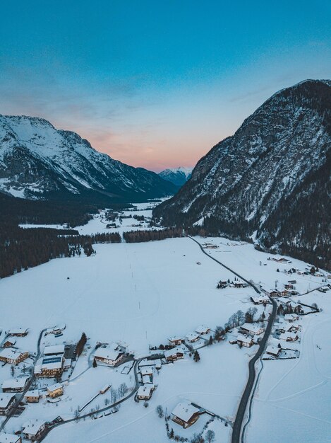 Breathtaking shot of a mountain range with a town below it in winter during sunset