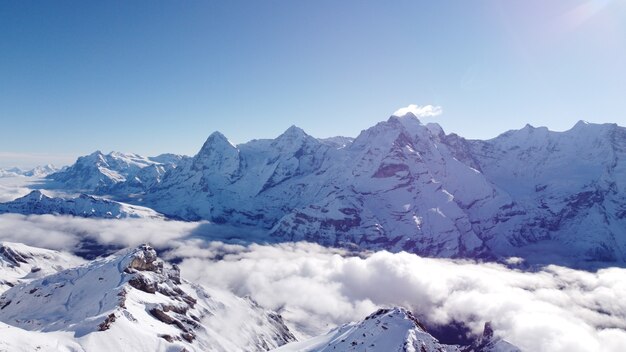 Захватывающий снимок пика заснеженных Альп, покрытых облаками.
