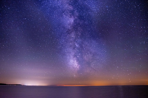 星に満ちた暗く紫色の空の下の海の息を ⁇ むショット