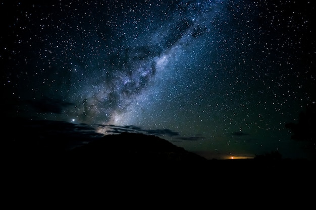 Захватывающий снимок силуэтов холмов под звездным небом в ночи.
