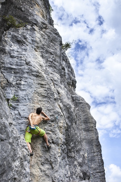 Захватывающий снимок молодого мужчины, взбирающегося на высокую скалу в Шампфромье, Франция.