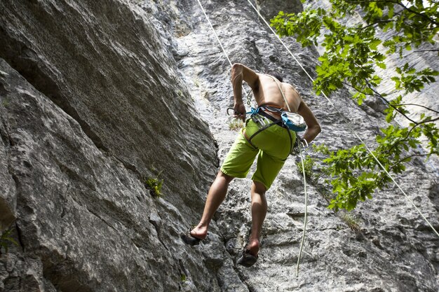 Breathtaking shot of a young male climbing on the high rock in  Champfromier, France