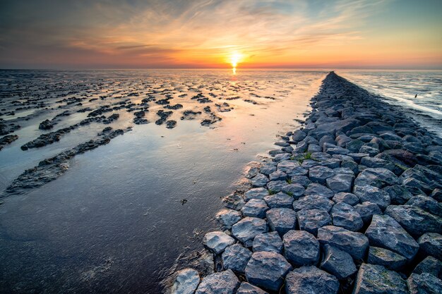 Breathtaking view of mudflat of the Waddenzee during low tide under amazing sunset sky with clouds