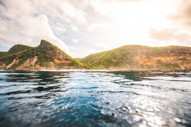 Breathtaking view of the ocean and cliffs covered with plants captured in Lombok, Indonesia