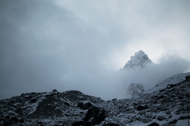 Breathtaking view of the snowy mountain summit in a foggy weather