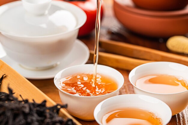 茶の儀式のクローズアップ中に陶器のガイワンで中国茶を造している
